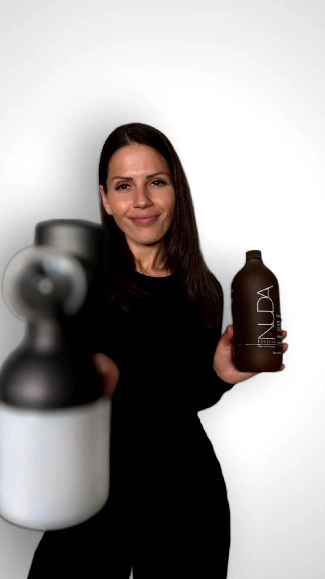 Ana Maria, NUDA certified spray tanning artist at GLOW17, with her airbrush gun and a NUDA bottle
